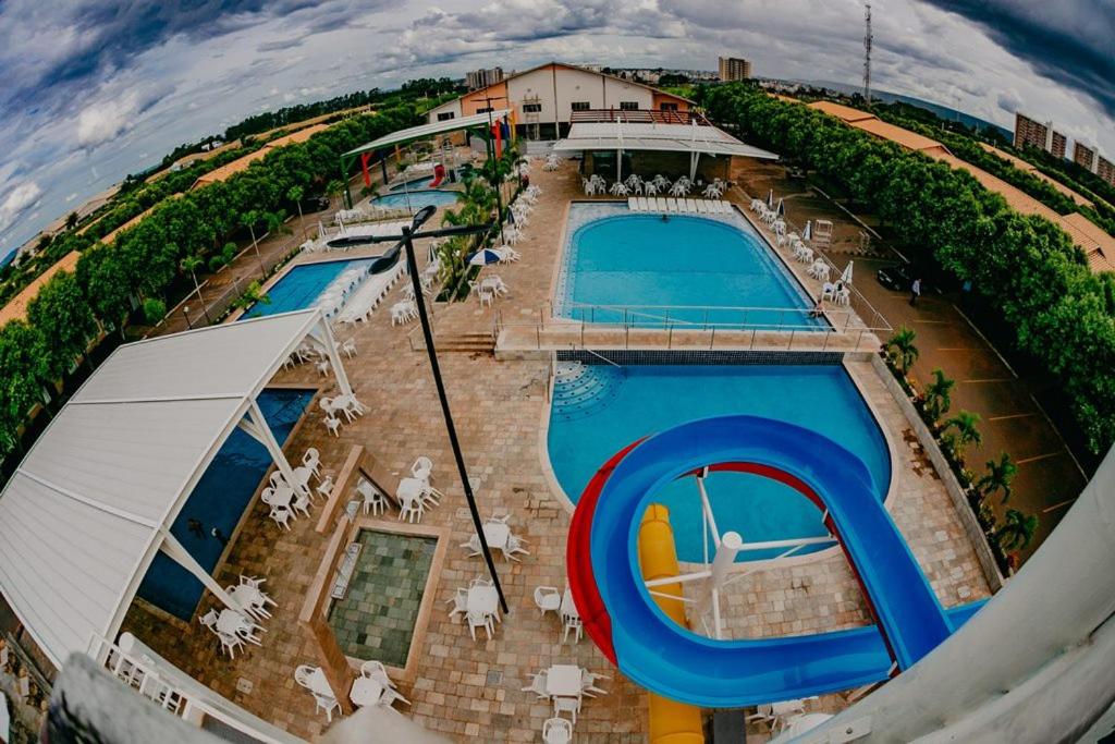 Parte de fora do DiRoma Fiori Hotel - BVTUR que mostra o tobogã colorido que dá para a piscina azul, ao lado outras piscinas cobertas e ao ar livre, algumas cadeiras espalhadas e algumas plantas em volta, ilustrando post Hotéis em Caldas Novas.