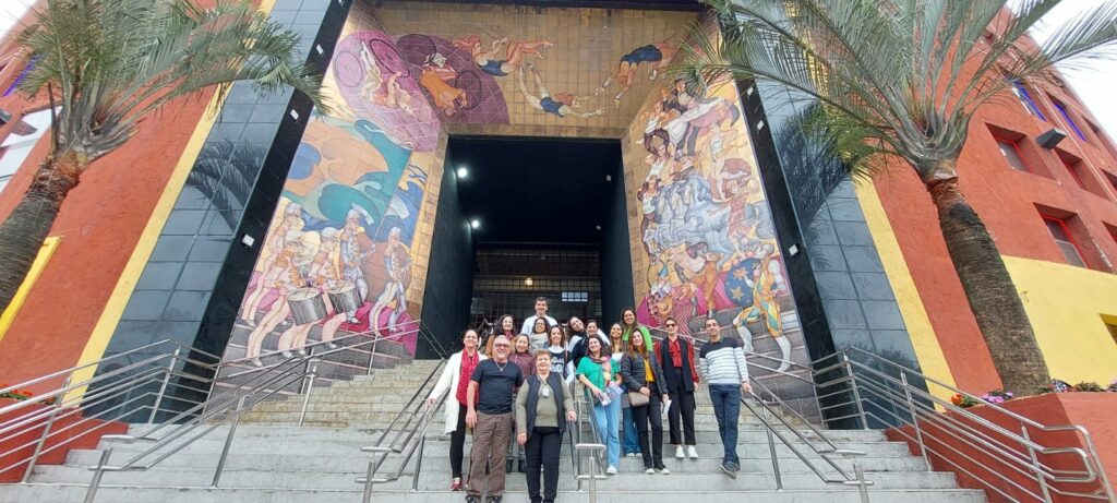 mural pintado pelo artista plástico Juarez Machado na entrada no Centreventos Cau Hansen - no qual acontece o Festival de Dança de Joinville, onde há uma grande escadaria com um grupo de pessoas diversas posando para a foto.