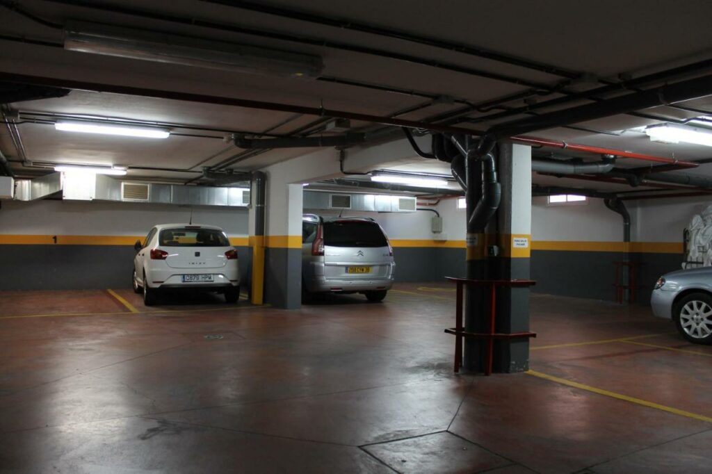 Estacionamento subterrâneo do Hotel Barajas Plaza. Três carros podem ser vistos parados ali, enquanto cinco outras vagas estão desocupadas.