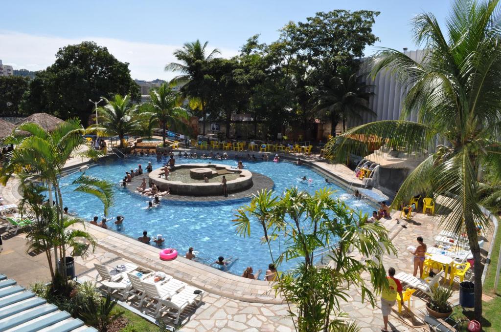 Imagem da parte de fora do Hotel CTC que mostra a piscina com bastante gente, algumas cadeiras amarelas em volta e também algumas árvores, ilustrando post Hotéis em Caldas Novas.