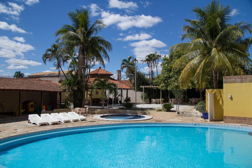 Parte de fora do Hotel Morada das Águas que mostra a piscina azul com algumas cadeiras para deitar, uma pequena piscina redonda e algumas árvores em volta durante o dia, ilustrando post Hotéis em Caldas Novas.
