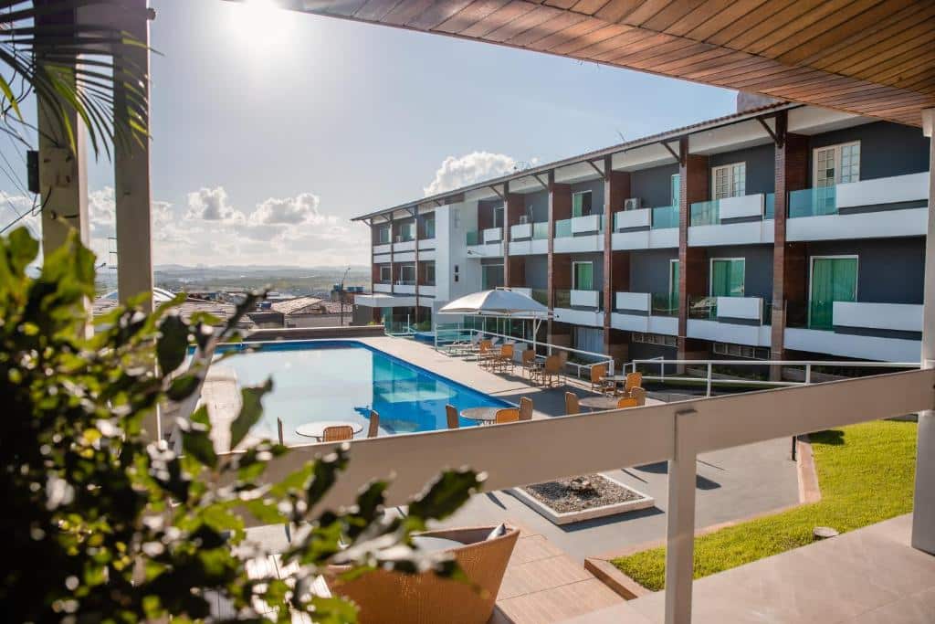 Piscina azul a esquerda, cadeiras amarelas a direita e quartos de hotel com varanda também a direita visto de uma varanda. Imagem para ilustrar o post hotéis em Caruaru.