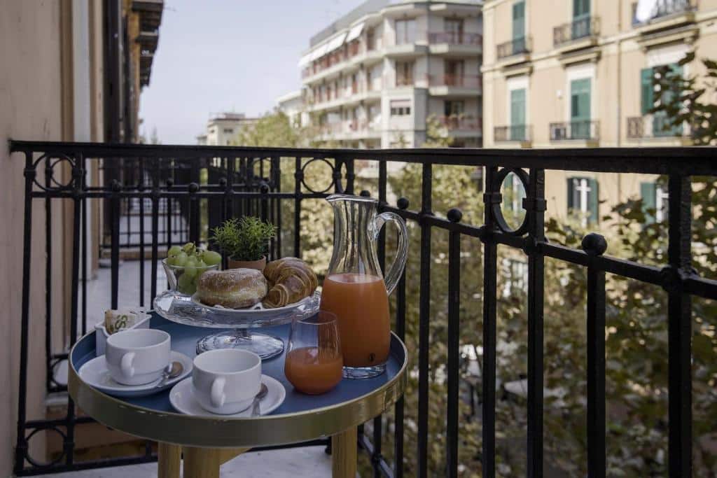 Sacada de grade do La Chambre com uma mesinha redonda com duas xícaras, uma jarra de suco e algumas guloseimas no prato, ilustrando post Hotéis em Nápoles.