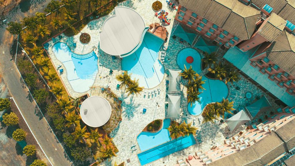 Foto aérea do Lagoa Quente Hotel que mostra quatro piscinas de tamanhos diferentes, algumas árvores e outras construções em volta.