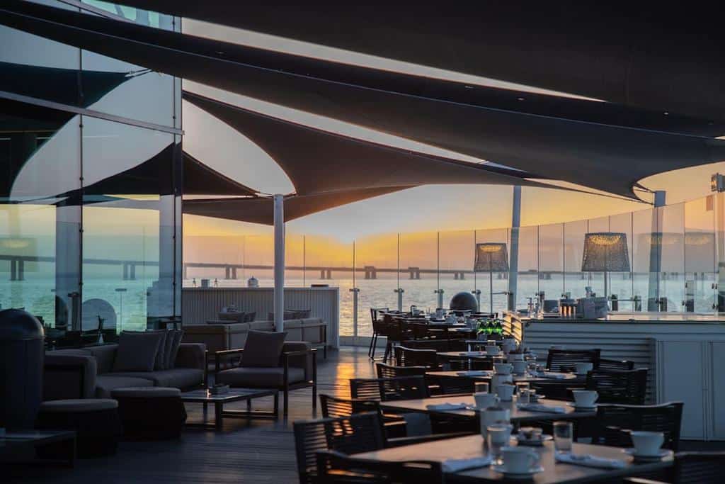 Área de refeições do MYRIAD by SANA Hotels com vista para o Rio Tejo cercado por uma estrutura de vidro