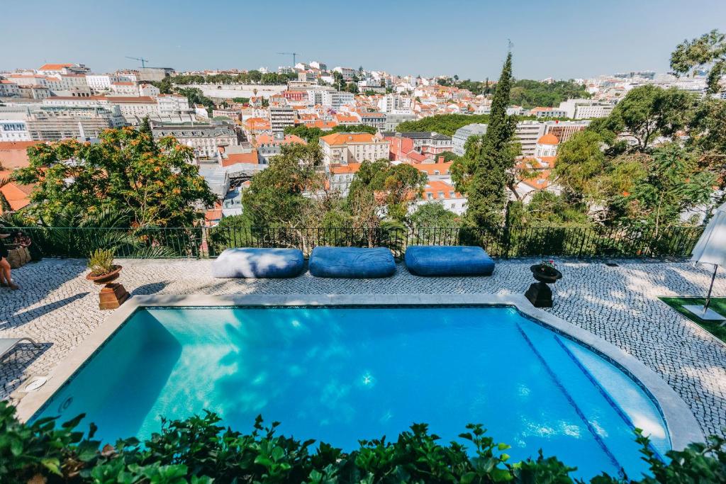 Piscina do Torel Palace Lisbon com vista direta para a cidade, há algumas almofadas grandes no deck na piscina
