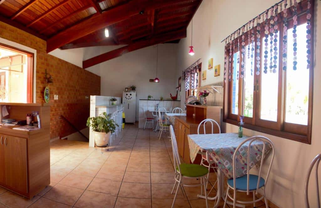 Foto de uma área comunitária na Estrela da Manhã Pousada. Há uma cozinha com itens essenciais como mesas, cadeiras, bancada, geladeira, etc.