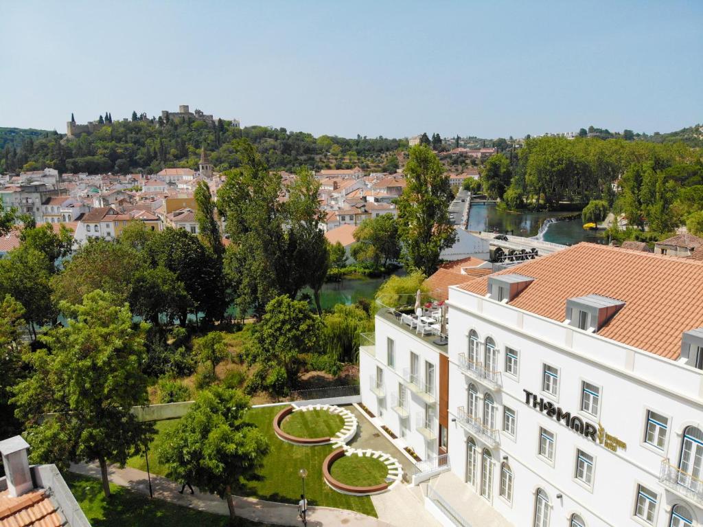 Propriedade do Thomar Boutique Hotel vista de cima, a construção é branca, há um jardim na frente e um terraço virado  para a cidade e as montanhas, para representar hotéis românticos em Lisboa