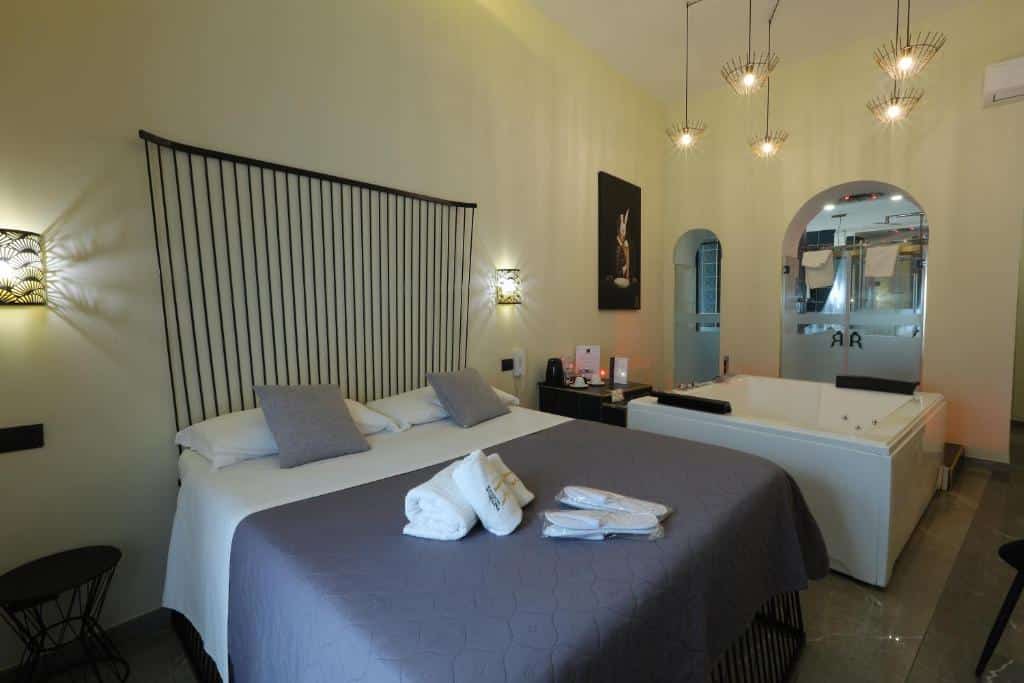 Quarto do Il Salotto della Regina com uma cama de casal ao centro do quarto, uma banheira de hidromassagem do lado direito da cama e atrás uma porta de vidro que dá acesso ao banheiro.