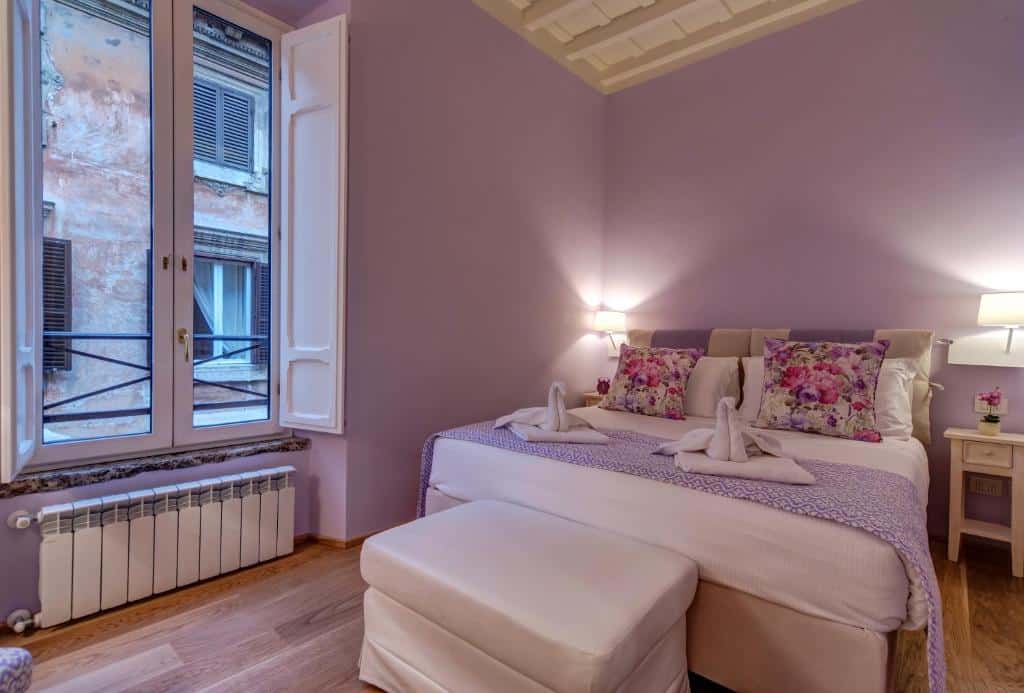 quarto do La Porta Rossa di Borgo - Vatican Luxury Suite, um airbnb em Roma, com janela e cortinas, aquecedor abaixo, cama bem grande, mesinha de cabeceira e luminária de ambos os lados e paredes lilás