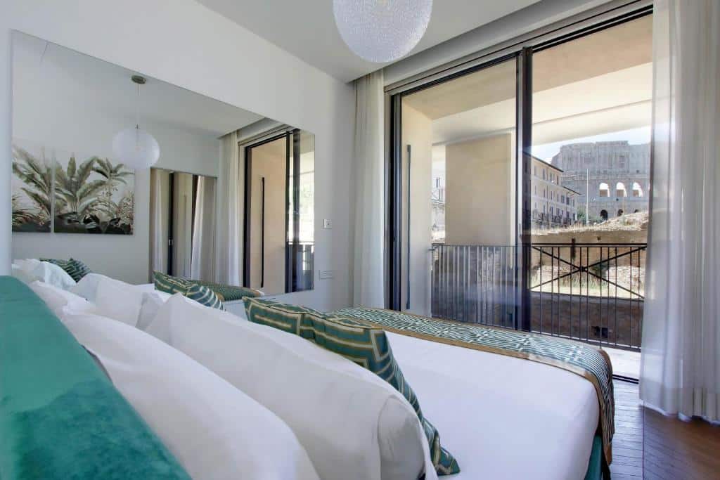 quarto do Luxury Domus Apartment 1, um aluguel de temporada em Roma, com cama bem grande com detalhes em verde e janelas de vidro que dão em uma varanda com mesinhas e cadeiras e vista direta do Coliseu