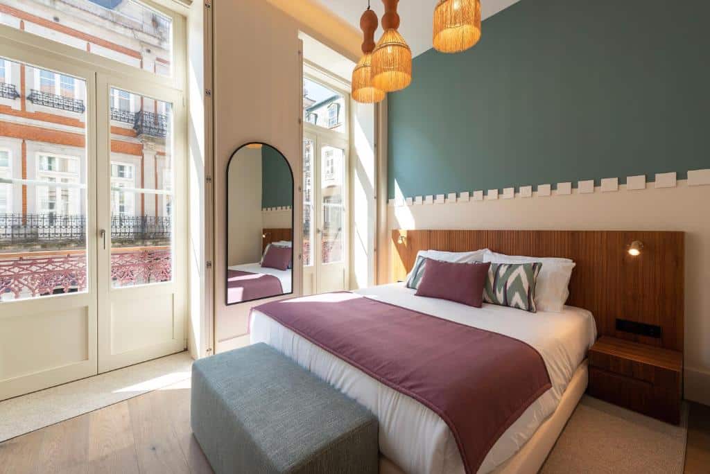 Quarto do Ando Living – Santa Catarina Townhouse com cama de casal do lado direito da imagem, no pé da cama um banco baú estofado cinza. Representa aluguel de temporada no Porto.