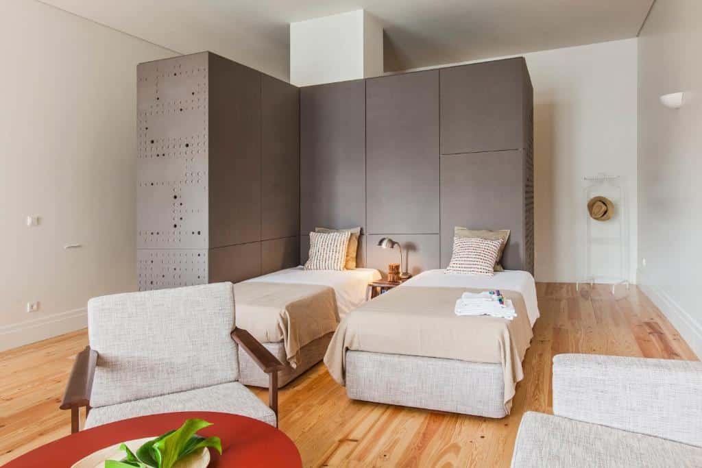 Quarto  do bnapartments Loftpuzzle com duas camas de solteiro a frente uma do lado da outra separado por uma pequena cômoda com luminária. Representa aluguel de temporada no Porto.