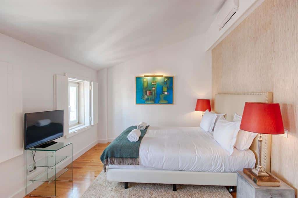 Quarto do Dear Lisbon - Charming House com uma cama de casal ampla com uma pequena janela de frente, há um ar-condicionado de teto, um quadro e uma televisão no ambiente