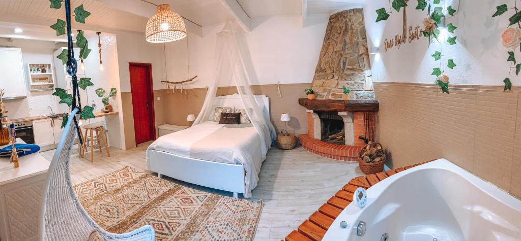 Quarto do Douro Rural Suite com cama de casal no centro do quarto, com lareira do lado direito e ao lado da lareira banheira de hidromassagem, no lado esquerdo do ambiente uma pequena cozinha. Representa airbnb no Porto.