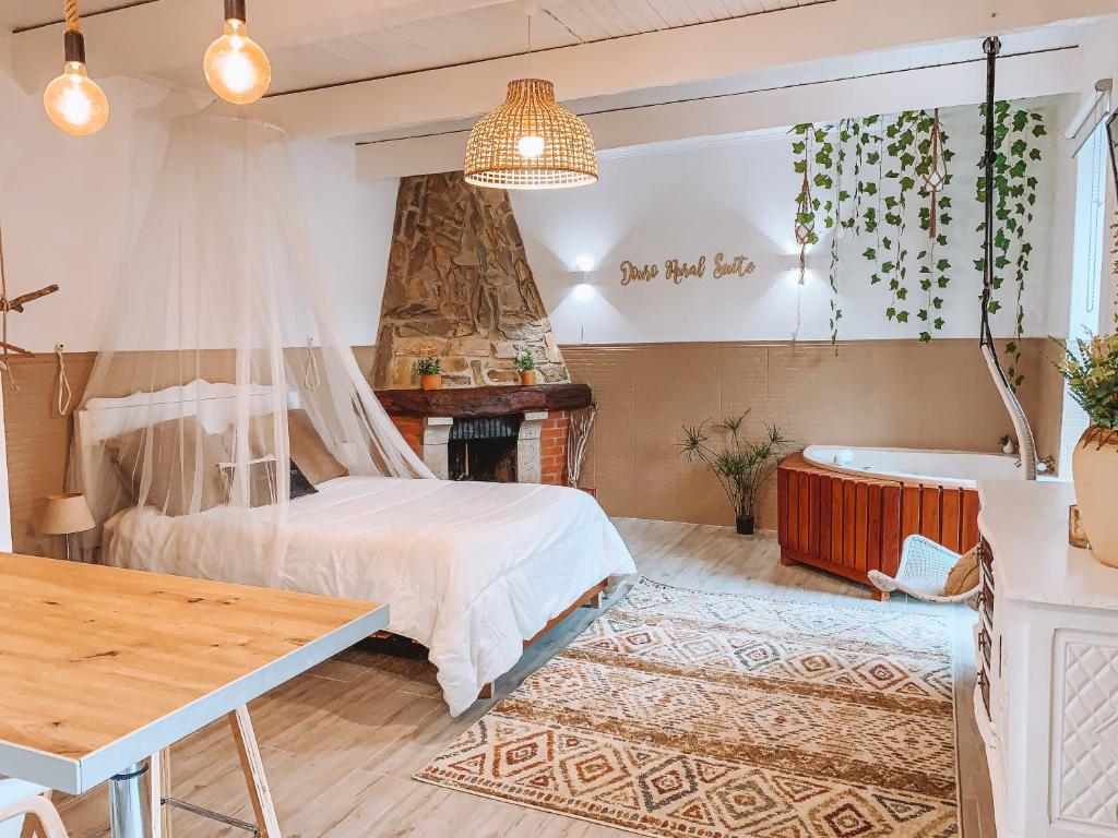 Quarto do Douro Rural Suite com cama de casal do lado esquerdo da imagem, do lado esquerdo da cama uma lareira e depois uma banheira de hidromassagem. Representa aluguel de temporada no Porto.