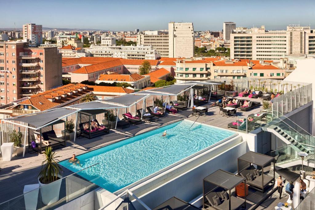 Piscina grande na cobertura do EPIC SANA Lisboa Hotel  com muitas espreguiçadeiras embaixo de toldos, para representar hotéis no centro de Lisboa