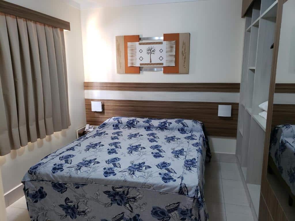 Quarto do Lacqua Di Roma Acqua Park com cama de casal no centro da imagem e uma cômoda do lado esquerdo da cama com telefone.