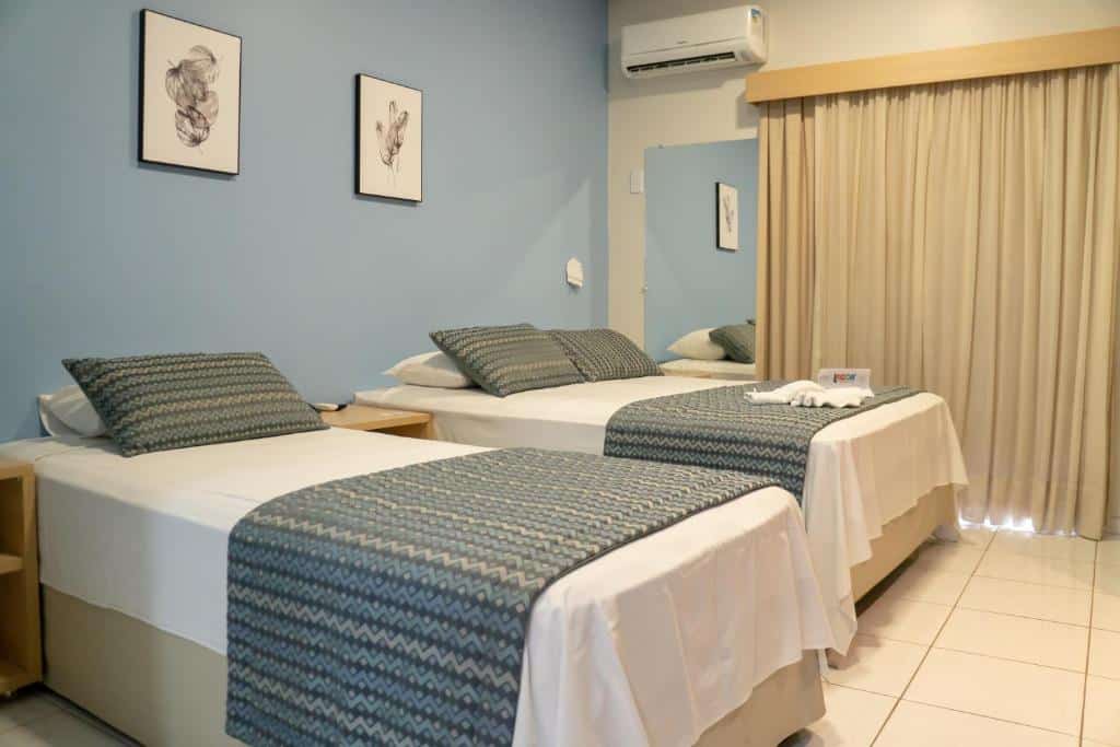 Quarto do Lagoa Quente Hotel com cama duas camas do lado esquerdo da imagem. Sendo uma cama de solteiro do lado esquerdo e do lado direito uma cama de casal. Representa resorts em Caldas Novas.