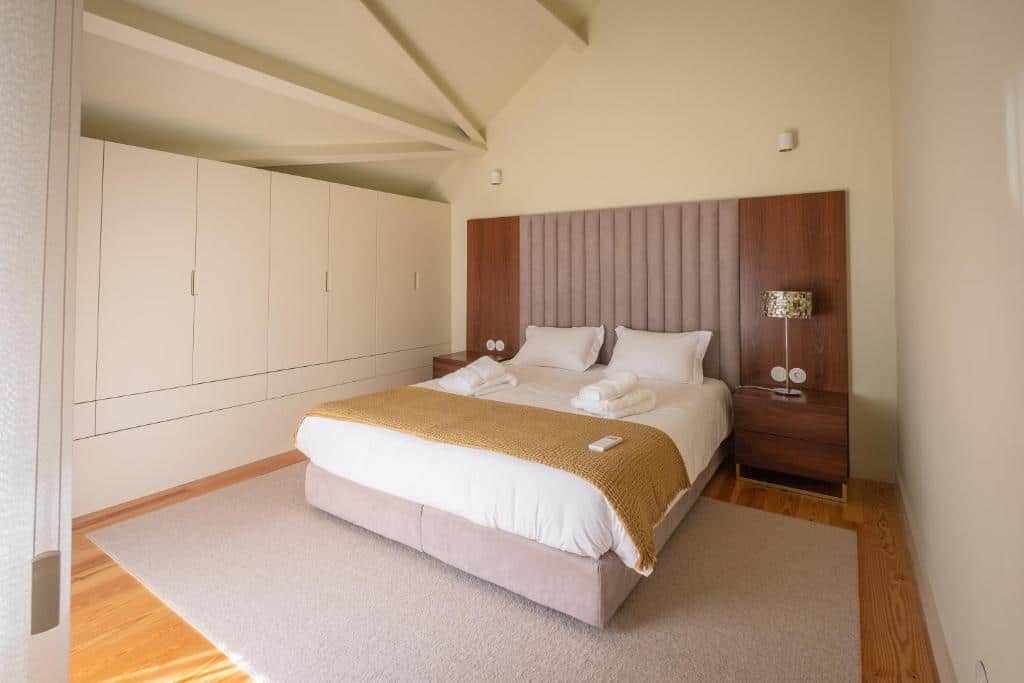 Quarto do Oporto INNside House com cama de casal do lado direito da imagem, duas cômodas em cada lado da cama e do lado direito da cama em cima da cômoda uma luminária.
