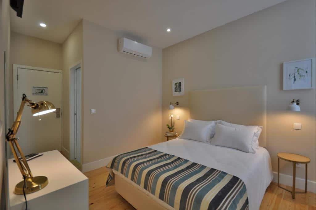 Quarto do Porto Charming Hotel com cama de casal do lado direito, com duas cômodas ao lado da cama e em frente a cama uma cômoda. Representa onde ficar no Porto.
