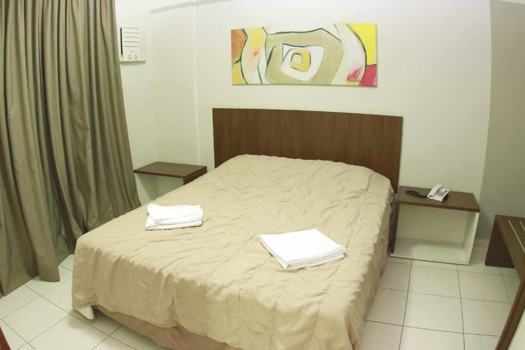Quarto do Prive Boulevard Thermas - OFICIAL com uma cama de casal, móveis de madeira do lado da cama, quadro na parede e uma cortina.