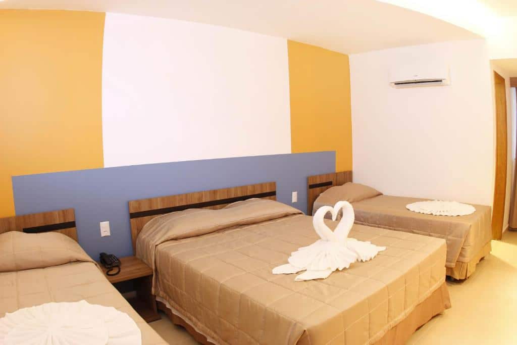 Quarto do Prive Thermas - OFICIAL com uma cama de casal e duas de solteiro, alguns móveis de madeira e ar condicionado na parede.