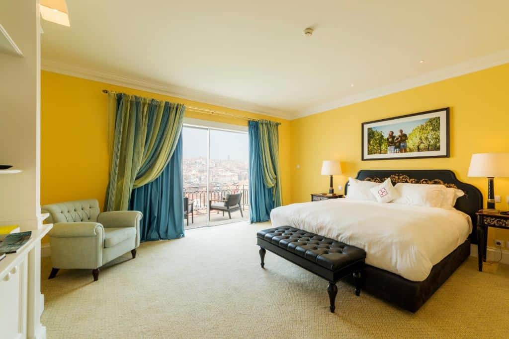 Quarto do The Yeatman com cama de casal do lado direito da imagem com uma cômoda em cada lado da cama com luminárias do lado esquerdo da cama uma poltrona. Representa onde ficar no Porto.