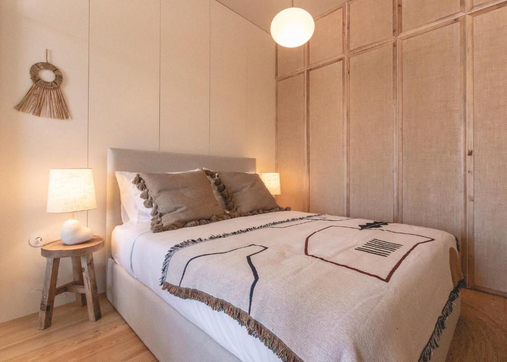 Quarto do Village Aparthotel By BOA com cama de casal do lado esquerdo, com duas cômodas ao lado da cama com luminária. Representa aluguel de temporada no Porto.