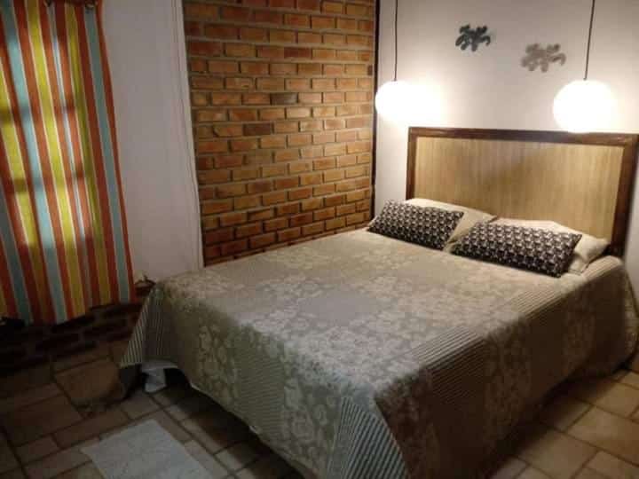 Quarto do Vivenda Peixe Pequeno. Uma cama de casal com um lustre pendurado de cada lado da cama.