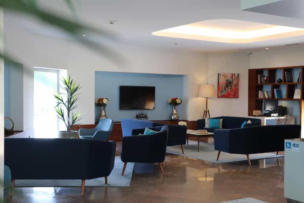 Sala da recepção do OPOHOTEL Porto Aeroporto com várias poltronas e sofás no ambiente e uma TV.
