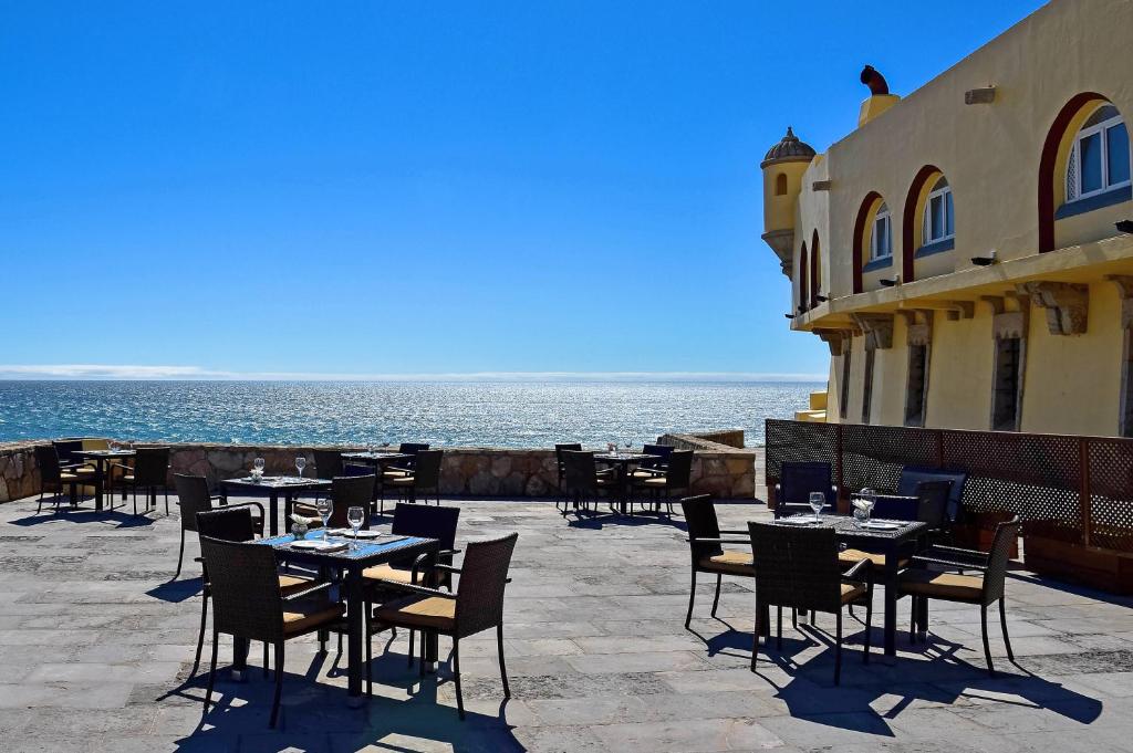 Terraço aberto com mesas e cadeiras no Hotel Fortaleza do Guincho Relais & Châteaux com uma vista incrível para o mar, para representar hotéis românticos perto de Lisboa