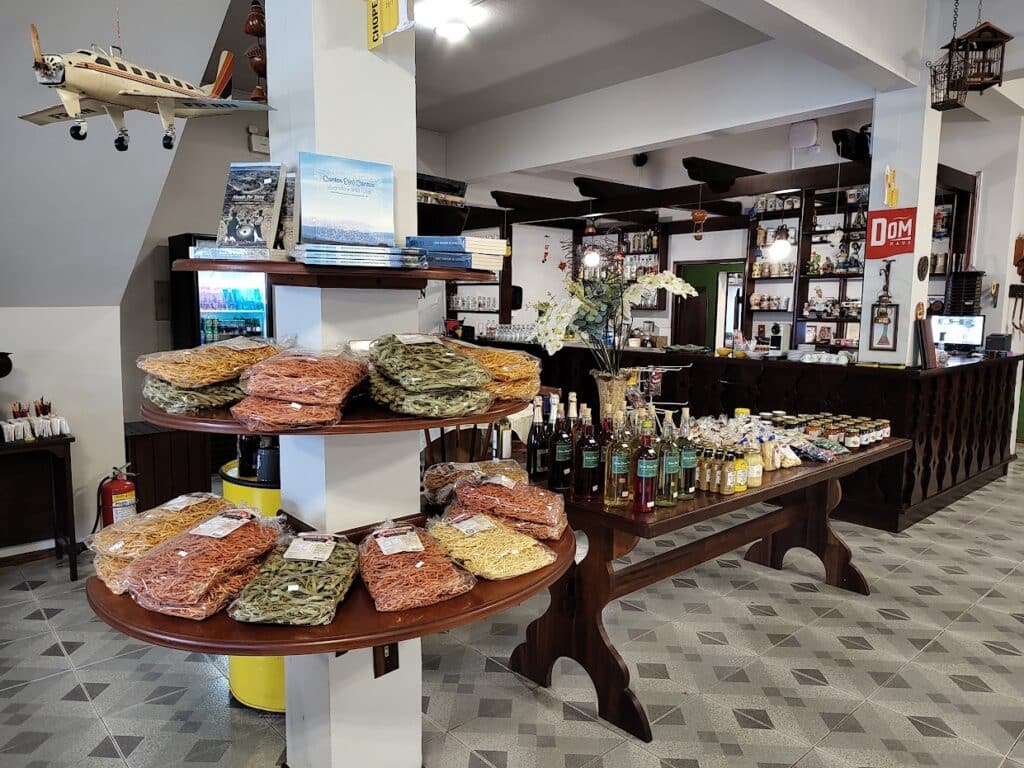 interior do restaurante Hübener com vários produtos artesanais dispostos para venda, incluindo massas de macarrão, azeite, geleias e afins