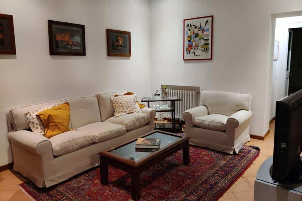 sala do Lanza Tomasi Apartment - centre, com sofás, mesinha de centro com tampo de vidro e tapete no chão, com tv à frente, o ambiente é não muito amplo