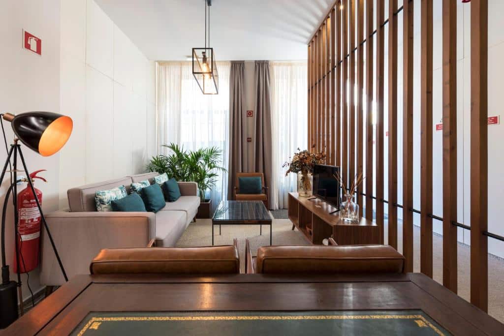 Sala de estar do Bloom House by Sweet Porto com sofá do lado esquerdo da imagem com uma mesa de centro e em frente ao sofá um rack com TV.