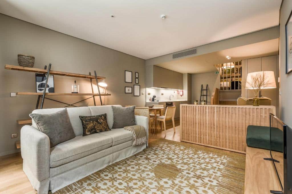 Sala de estar do Legends House by Sweet Porto a frente com sofá do lado esquerdo, um rack com TV em frente ao sofá, do lado esquerdo da imagem ao fundo uma cozinha.