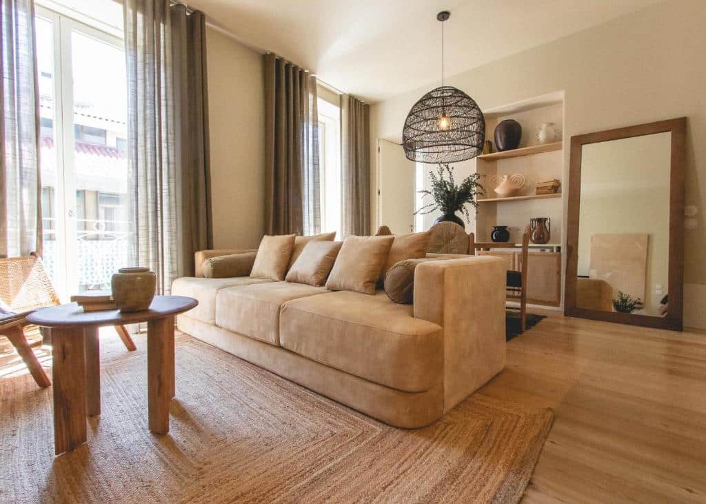 Sala de estar do Village Aparthotel By BOA com sofá do lado direito uma pequena mesa redonda de madeira em frente ao sofá.