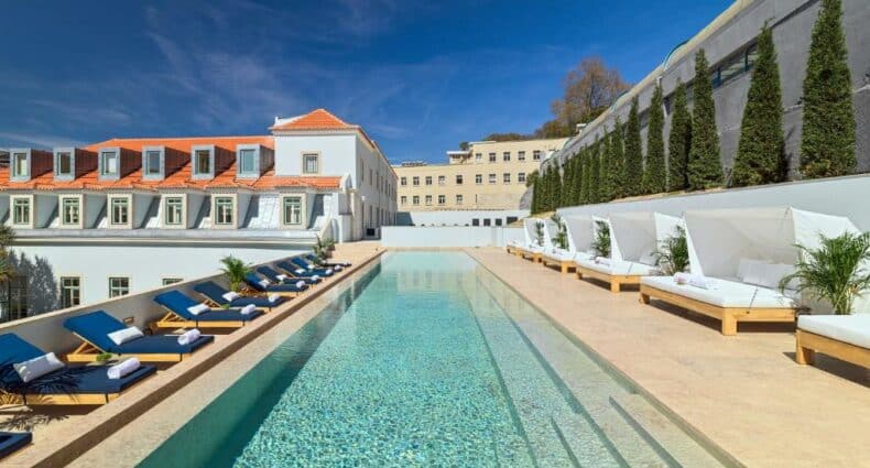 Piscina do The One Palácio da Anunciada em um terraço alto com espreguiçadeiras nos dois lados da piscina, para representar hotéis com piscina em Lisboa