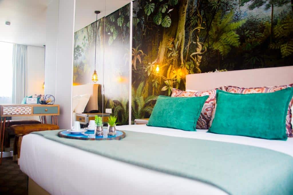 Quarto do Thomar Boutique Hotel com destaque para a cama de casal com almofadas coloridas e travesseiros, na cabeceira há um papel de parede que remete à natureza, para representar hotéis românticos em Lisboa
