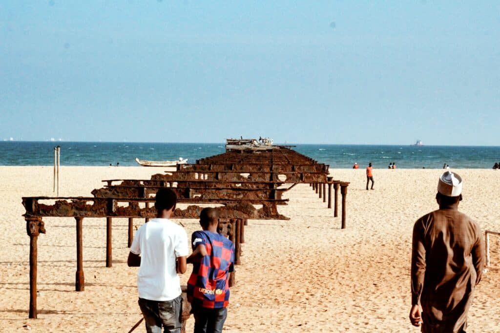 Homens na área da praia no Togo a frente e ao fundo o mar.