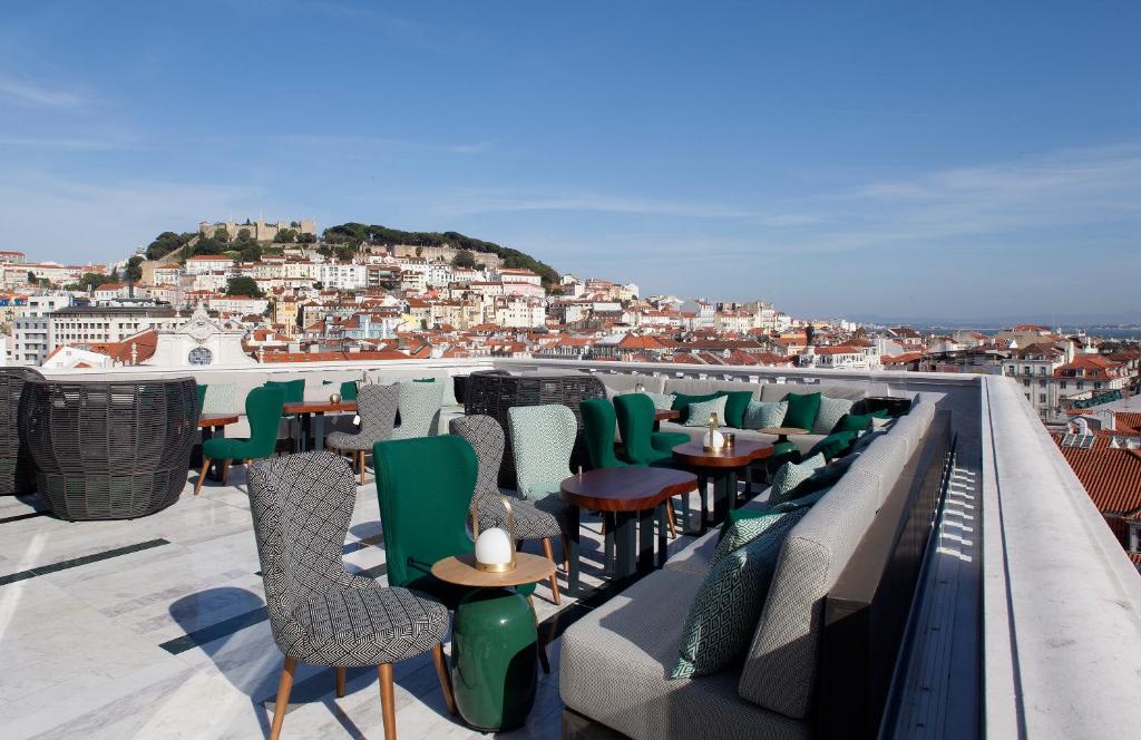 Terraço na cobertura do hotel Altis Avenida Hotel, no local há diversos sofás e poltronas estofadas em tons de verde e cinza, a vista ao redor inclui o Castelo de São Jorge