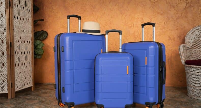 Três malas de tamanhos diferentes na cor azul com rodinhas laranjas, para representar extravio de bagagem