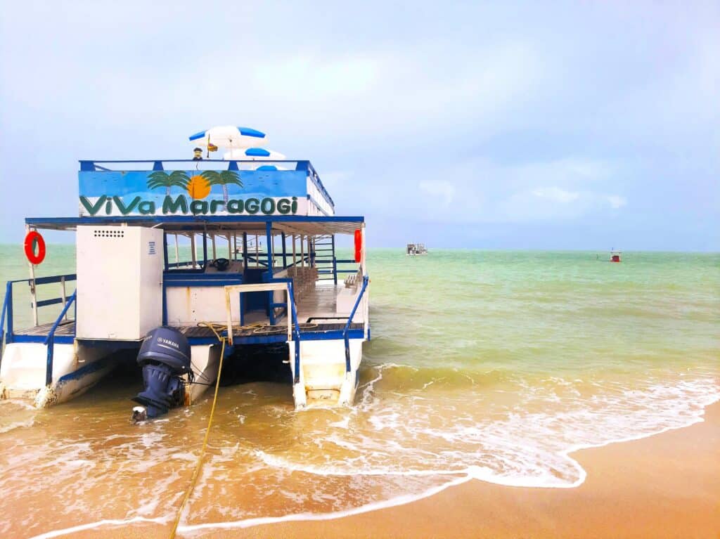 Barco na parte rasa de uma praia em Maragogi, escrito "Viva Maragogi"