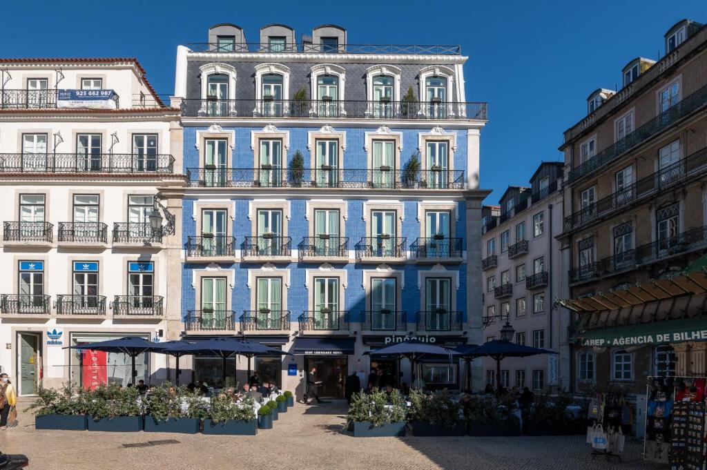 Propriedade do Blue Liberdade Hotel, trata-se de um prédio de época com seis andares pintado em azul claro com janelas brancas, o prédio está de frente para um pequeno pátio com comércio, para representar hotéis para brasileiros em Lisboa