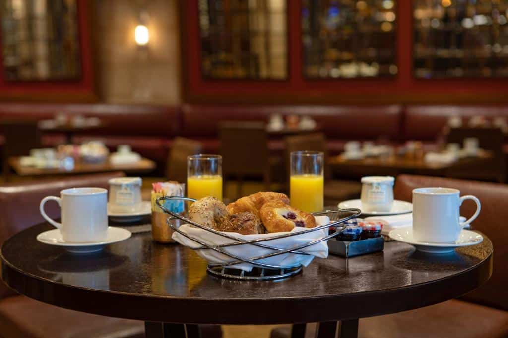 mesa de café da manhã do InterContinental New York Times Square, an IHG Hotel com uma cesta de pães e croissants recheados, dois copos de suco de laranja e duas xícaras de café.