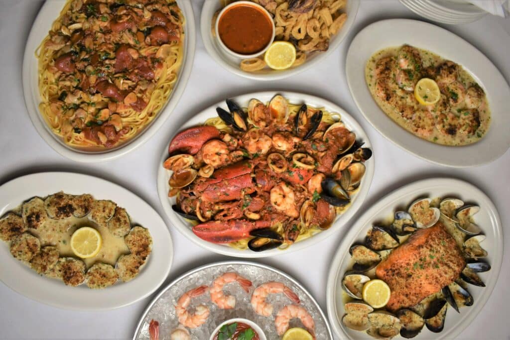 Diversos pratos com massa fresca e frutos do mar sob uma mesa no restaurante Carmine’s em Nova York
