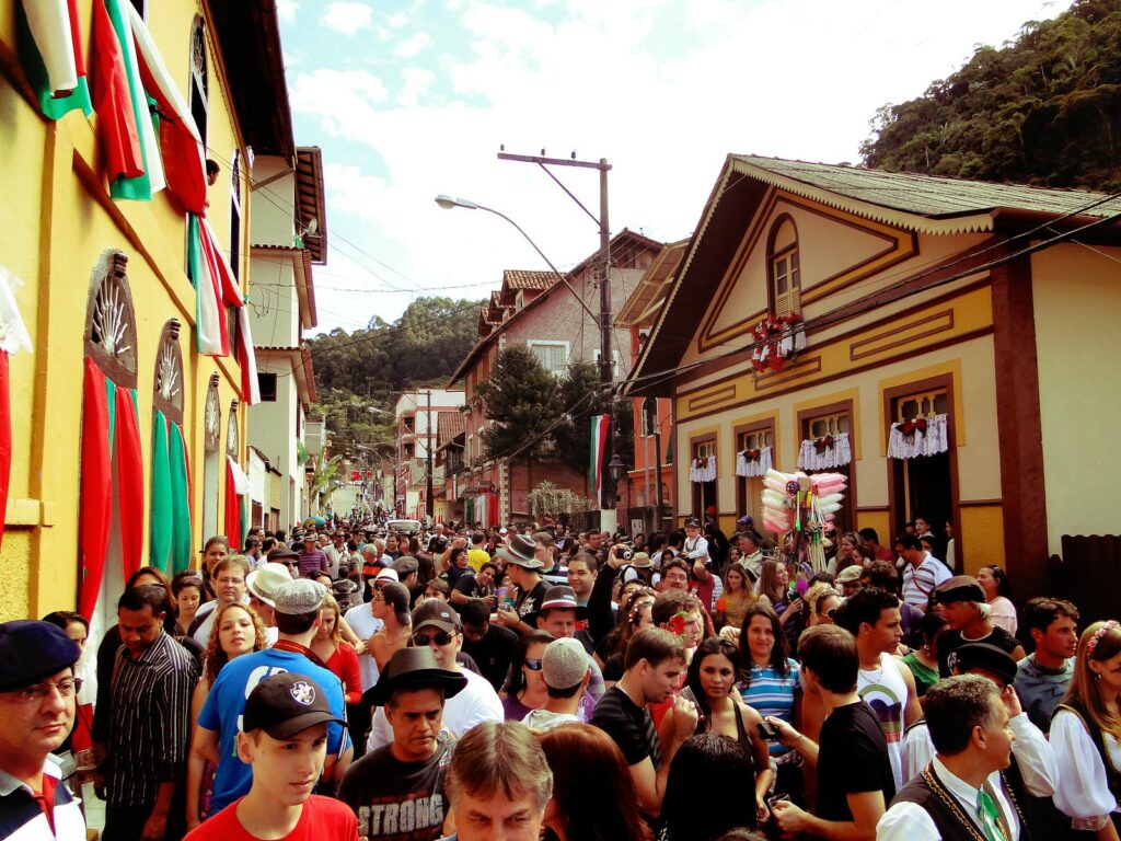 Imagem de pessoas na rua de Santa Teresa, no Espírito Santo, comemorando a festa do imigrante chamada Carretela del Vin.