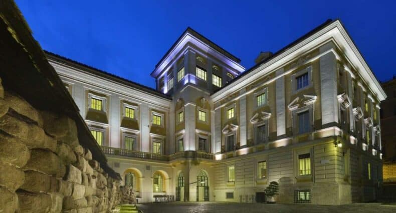 fachada do Palazzo Montemartini Rome, A Radisson Collection Hotel, um dos melhores hotéis em Roma, que parece um palácio com suas linhas retas e imponentes, além da bela iluminação à noite e muros de pedra ao redor