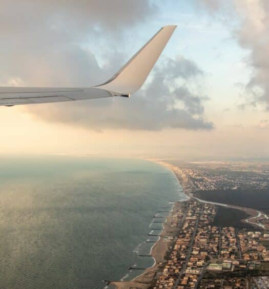 vista da asa de avião passando por cima do Fiumicino, uma cidadezinha à beira-mar, para ilustrar o post de aluguel de carros no Aeroporto de Roma