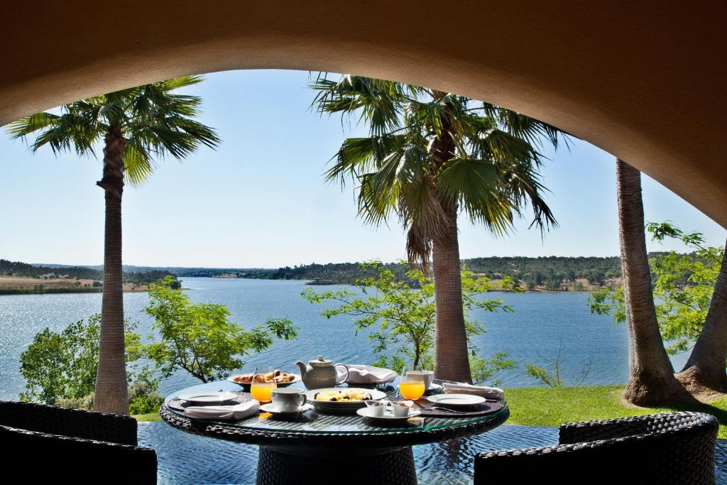 Mesa redonda com café da manhã e duas cadeiras no hotel Montargil Monte Novo com vista para um enorme lago.